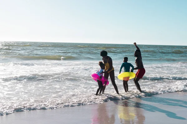 玩世不恭的非洲裔美国父母和孩子们 带着游泳的漂浮物 在清澈的天空中享受着大海的美景 复制空间 水和夏季概念 — 图库照片