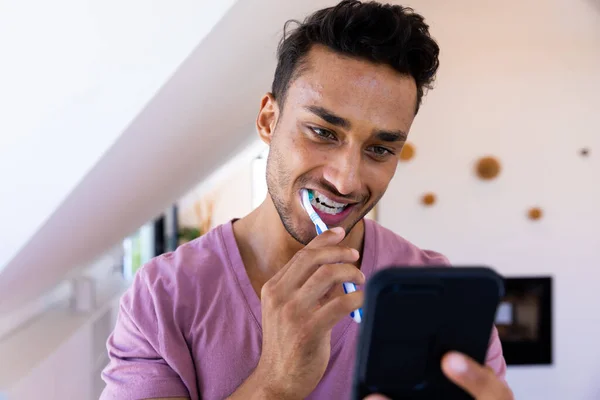Feliz Hombre Biracial Cepillarse Los Dientes Uso Teléfono Inteligente Baño — Foto de Stock