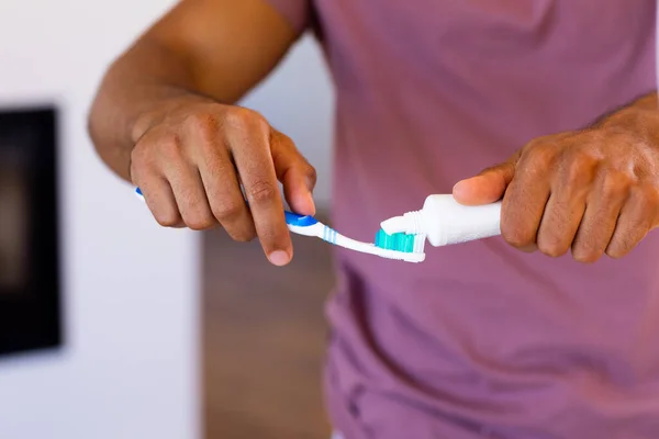 浴室の歯ブラシに歯磨き粉を置く出生男の中央部 ライフスタイル セルフケア 国内生活 変わらない — ストック写真