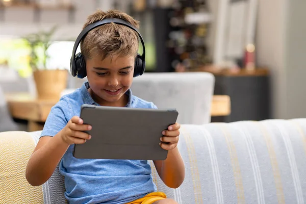 Biały Słodki Chłopiec Noszący Słuchawki Oglądający Wideo Przez Cyfrowy Tablet — Zdjęcie stockowe