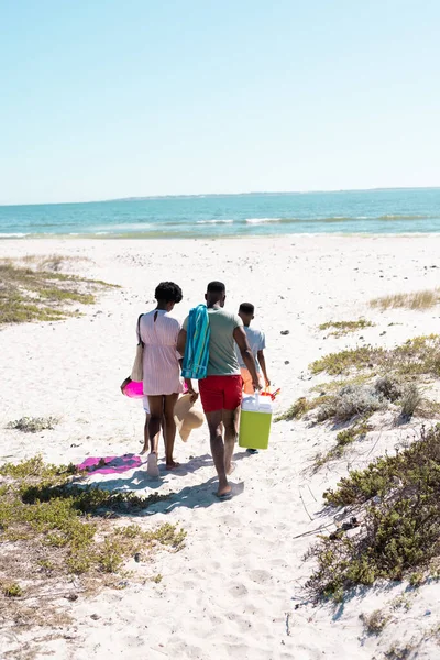 澄んだ空に向かって砂浜を歩いている子供を持つアフリカ系アメリカ人の両親の後部ビュー コピースペース 変更されていない 一緒に 子供時代 ピクニック 楽しみと夏 — ストック写真