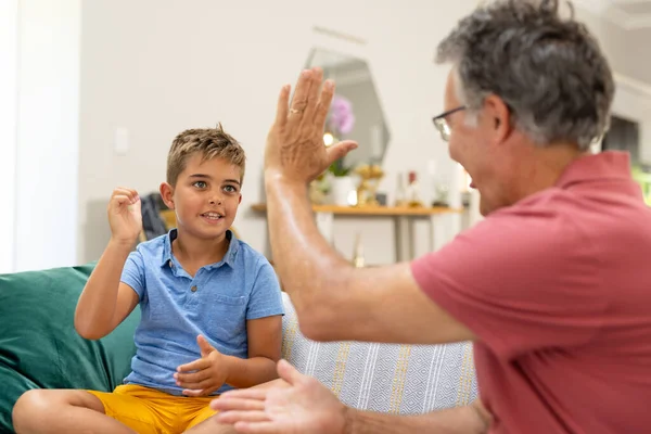 Caucasian Cute Boy Giving High Five Grandfather While Sitting Sofa — Stock Photo, Image