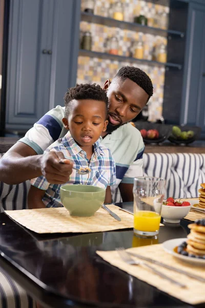 非裔美国父亲在家里的饭桌上给儿子吃早餐谷类食品 复制空间 生活方式 新鲜健康的概念 — 图库照片