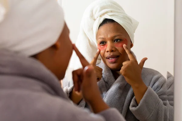 Šťastná Velká Africká Američanka Županu Maskou Očích Dívá Zrcadla Koupelně — Stock fotografie