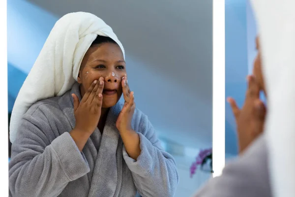 幸せプラスサイズアフリカ系アメリカ人女性は バスルームで顔クリームを適用し ローブを着て セルフケア 健康と美しさ 身体の包容力とライフスタイル 変わらない — ストック写真