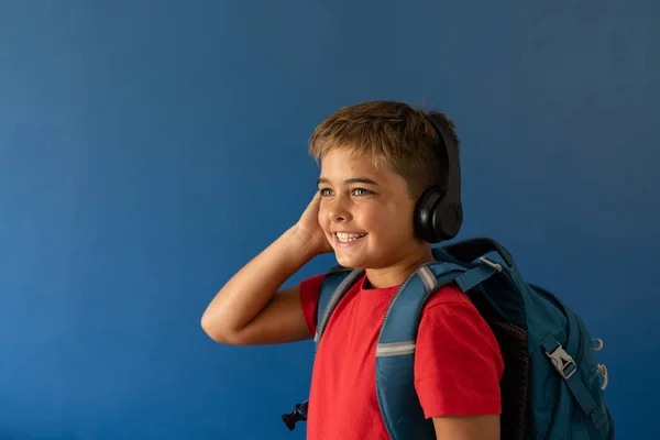 白人男孩头戴耳机背负盈亏站在蓝色背景 复制空间 不变的生活方式 科技和快乐的概念 — 图库照片