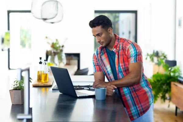 Homem Biracial Feliz Apoiando Bancada Tomando Café Usando Laptop Cozinha — Fotografia de Stock