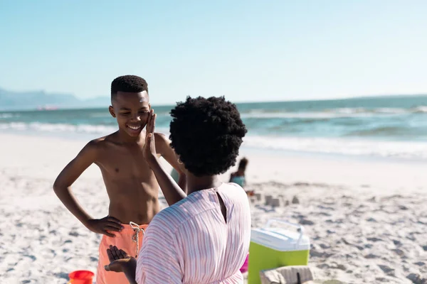 Африканская Американка Нанесла Солнцезащитный Крем Лицо Сына Пляже Против Чистого — стоковое фото