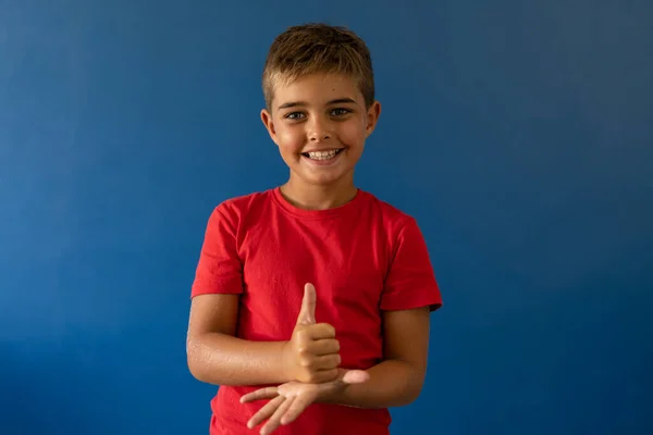 Portrait Cute Caucasian Boy Smiling Doing Hand Sign Blue Background — Stock Photo, Image