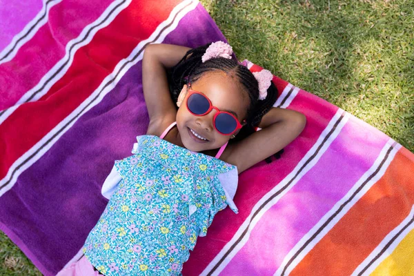 可爱的非洲裔美国女孩 戴着太阳镜 手后脑勺放在毛巾上 不变的生活方式 高瞻远瞩 放松和享受的概念 — 图库照片
