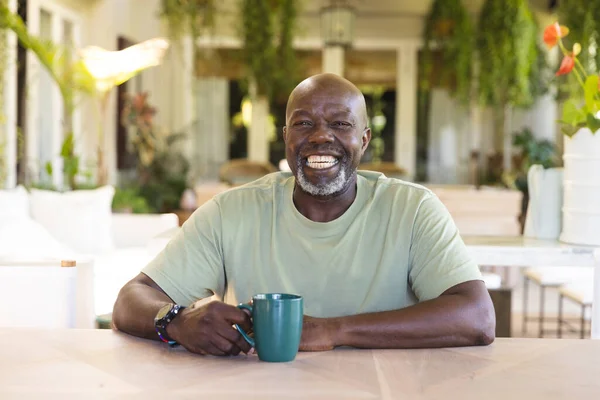 ビデオ通話を持つコーヒーを飲みながら幸せなシニアアフリカ系アメリカ人男性の肖像画 シニアライフスタイル テクノロジー 国内生活 — ストック写真