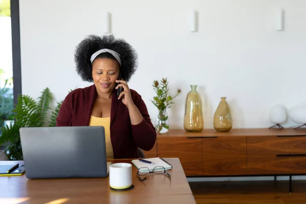 Щаслива Завбільшки Афро Американська Жінка Сидить Столом Використовуючи Ноутбук Розмовляючи — стокове фото