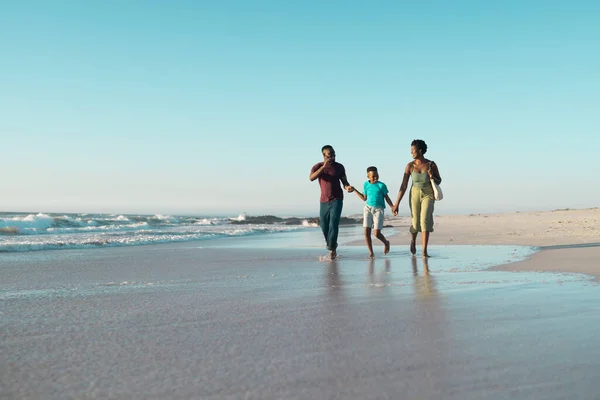 父と母の手を取り 空に対して海で走っている陽気なアフリカ系アメリカ人の少年 コピースペース 変更されていない 一緒に 子供時代 楽しさと夏のコンセプト — ストック写真