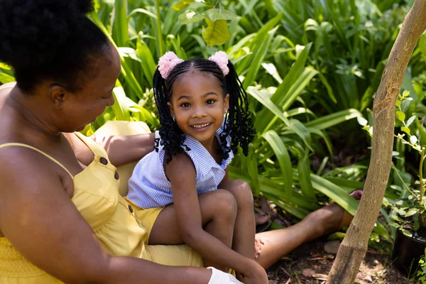 African American Smiling Girl Sitting Grandmother Plants While Gardening Yard — Stock Photo, Image