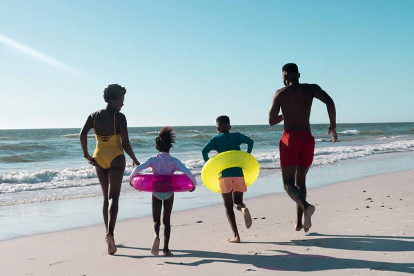 장난기많은 아프리카 미국인 부모와 수영하는 가지고 바다를 달리는 아이들의 뒷모습 — 스톡 사진