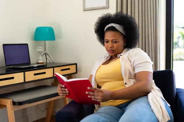 Плюс Большая Африканская Американка Сидящая Дома Кресле Сосредоточенная Чтении Книги — стоковое фото