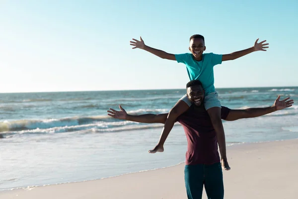 Estatico Padre Afroamericano Che Porta Figlio Sulle Spalle Spiaggia Contro — Foto Stock