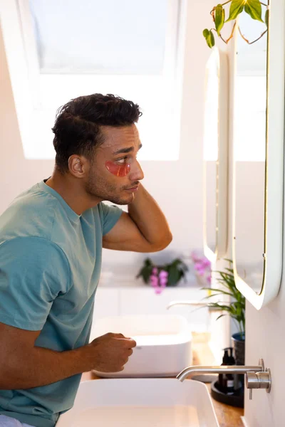 Biracial Homem Olhando Espelho Aplicando Sob Máscaras Oculares Banheiro Estilo — Fotografia de Stock