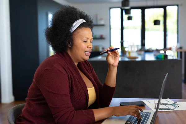 快乐加尺寸的非洲裔美国女人坐在桌旁 用笔记本电脑 在家工作 身体包容和生活方式 — 图库照片