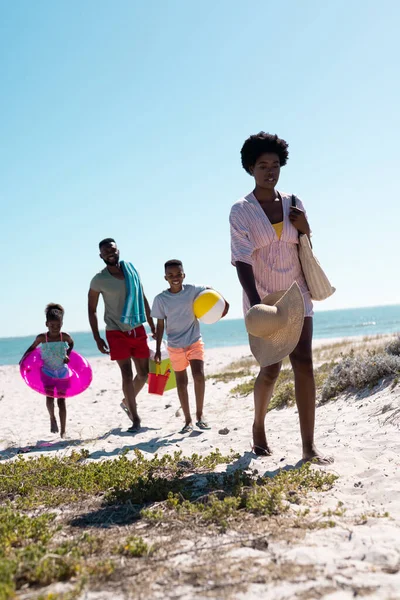 アフリカ系アメリカ人の両親と子供たちは休暇中に澄んだ青い空に対して砂浜を歩いています コピースペース 変更されていない 一緒に 子供時代 ピクニック 楽しみ — ストック写真