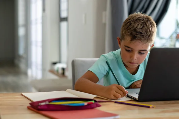 Kaukázusi Fiú Jegyzetel Miközben Házi Feladatot Laptopon Keresztül Otthon Helyet — Stock Fotó