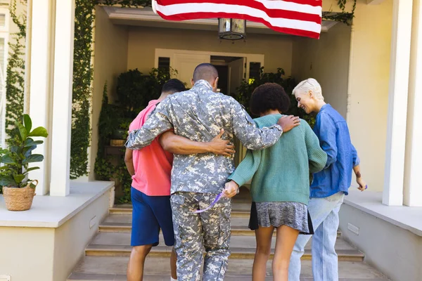 Lykkelig Mangfoldig Vennegjeng Som Hilser Etnisk Amerikansk Soldat Utenfor Huset – stockfoto