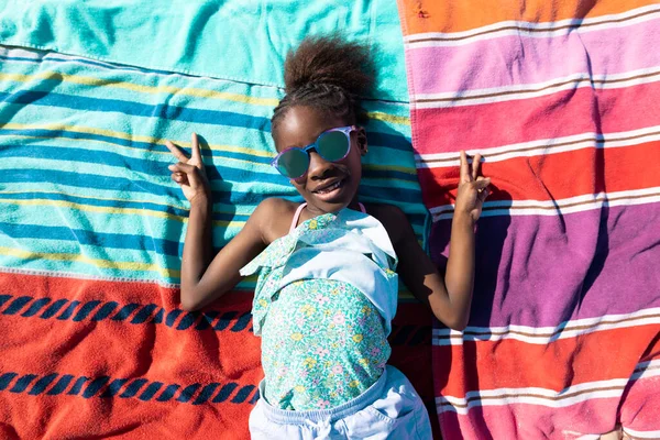 Szczęśliwa Afroamerykanka Okularach Przeciwsłonecznych Pokazująca Znak Pokoju Leżąc Ręcznikach Plaży — Zdjęcie stockowe