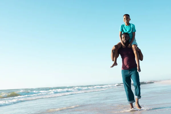 Счастливый Африканский Отец Американец Несущий Сына Плечах Идущий Берегу Моря — стоковое фото