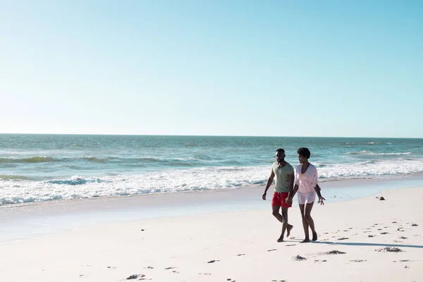 美しい海と空に対して砂のビーチで話して歩くアフリカ系アメリカ人の大人のカップル コピースペース 変更されていない 楽しさと夏のコンセプト — ストック写真