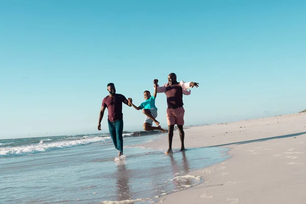 アフリカ系アメリカ人の父と祖父は少年の手を握って空の下で海岸で彼を拾う コピースペース 変更されていない 多世代家族 一緒に 子供時代 楽しみ — ストック写真