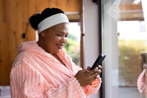快乐加尺寸的非洲裔美国女人 身穿长袍 头戴头巾 在温泉用智能手机 健康与美 身体包容 沟通和生活方式 — 图库照片