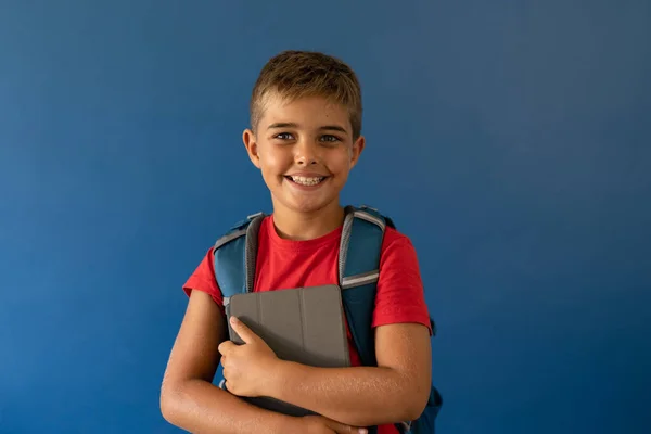 Sırt Çantalı Dijital Tabletli Beyaz Çocuk Mavi Arka Planda Duruyor — Stok fotoğraf