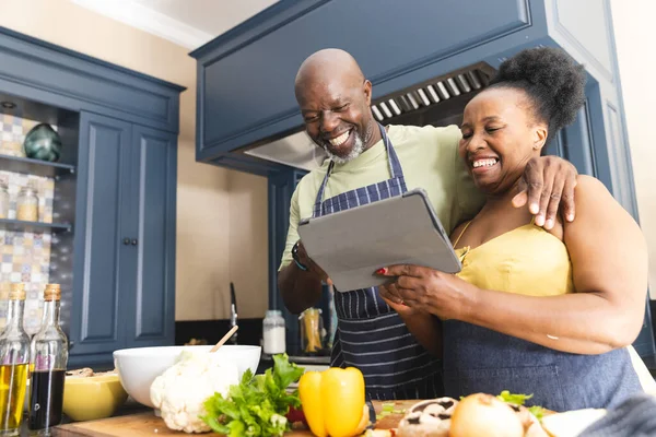 Ευτυχισμένο Ζευγάρι Αφροαμερικανών Που Φοράει Ποδιές Και Μαγειρεύει Τάμπλετ Στην — Φωτογραφία Αρχείου