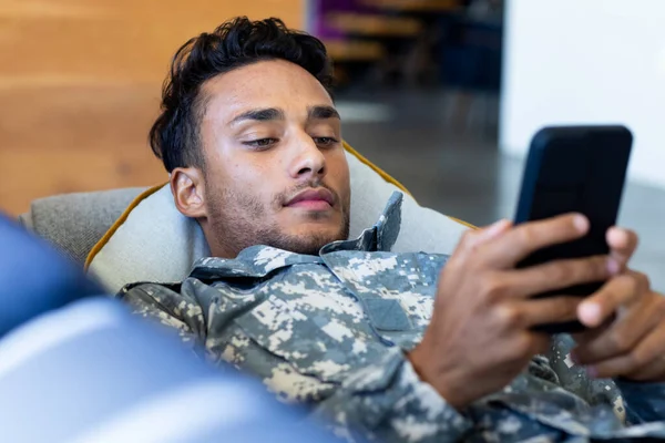 Soldado Masculino Biracial Vestindo Uniforme Deitado Sofá Usando Smartphone Estilo — Fotografia de Stock