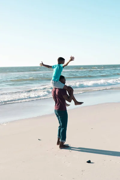 Веселый Африканский Американец Протянутыми Руками Сидящий Плечах Отца Пляже Копируй — стоковое фото