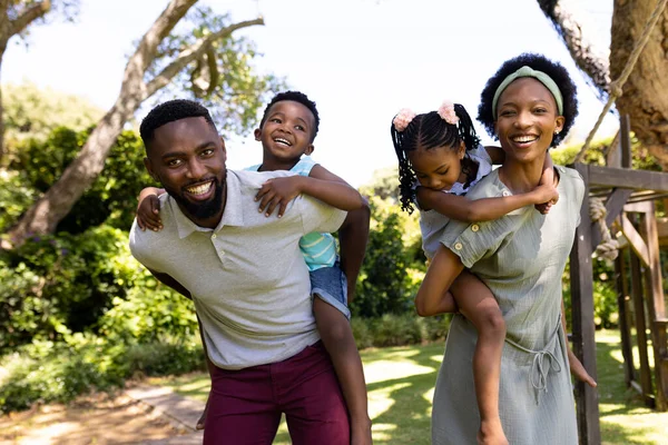 Afroamerikanische Eltern Huckepack Verspielte Sohn Und Tochter Während Sie Park — Stockfoto