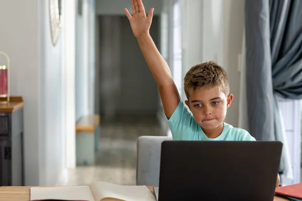 自宅でノートパソコンを介してオンラインクラスに出席しながら手を上げる白人少年 コピースペース 変更されていない 子供時代 無線技術 学生およびEラーニングの概念 — ストック写真