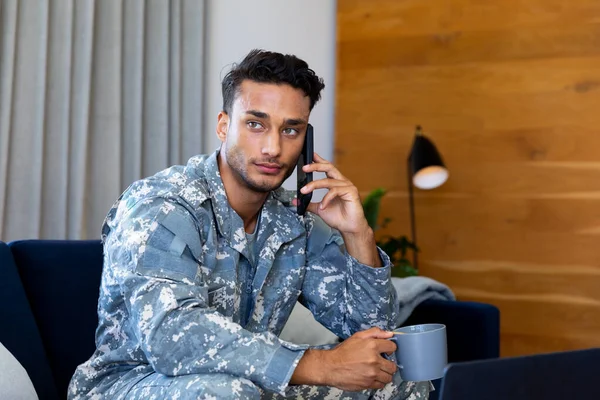 Tankeväckande Biracial Man Soldat Uniform Sitter Soffan Pratar Smartphone Vardagsrummet — Stockfoto