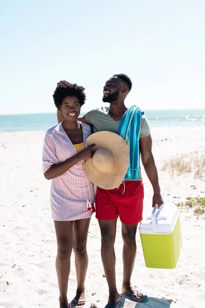 快乐的非洲裔美国男人在清澈的天空下 站在海滩上摸着妻子的非洲头发 复制空间 在一起 帽子和夏天 — 图库照片
