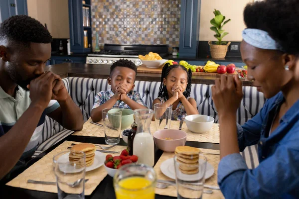 アフリカ系アメリカ人の両親と子供たちは 朝の朝食前にダイニングテーブルで優雅さを言います 変更されていない 一緒に 子供時代 食べ物 宗教と家庭の概念 — ストック写真