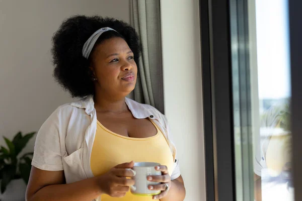 Düşünceli Cüsseli Afro Amerikan Kadın Pencereden Dışarı Bakıyor Elinde Kupa — Stok fotoğraf