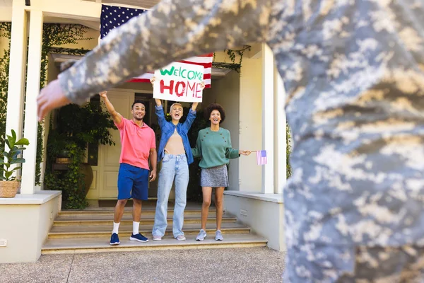 家の外で出産の男性のアメリカの兵士を迎える友人の幸せな多様なグループ アメリカの国旗 愛国心 — ストック写真
