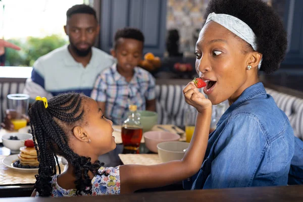 非裔美国人女儿在家里和家人一起吃早餐的时候给妈妈喂草莓 不变的家庭 新鲜和生活方式概念 — 图库照片