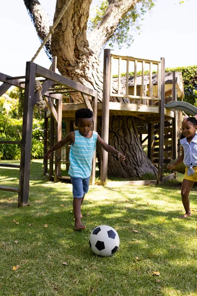 快乐的非洲裔美国兄弟姐妹在公园的草地上踢足球 不变的家庭 娱乐和周末概念 — 图库照片