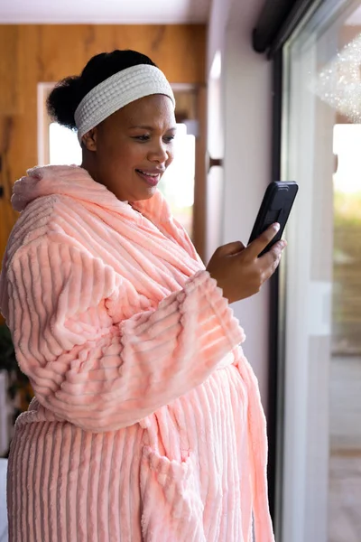 快乐加尺寸的非洲裔美国女人 身穿长袍 头戴头巾 在温泉用智能手机 健康与美 身体包容 沟通和生活方式 — 图库照片