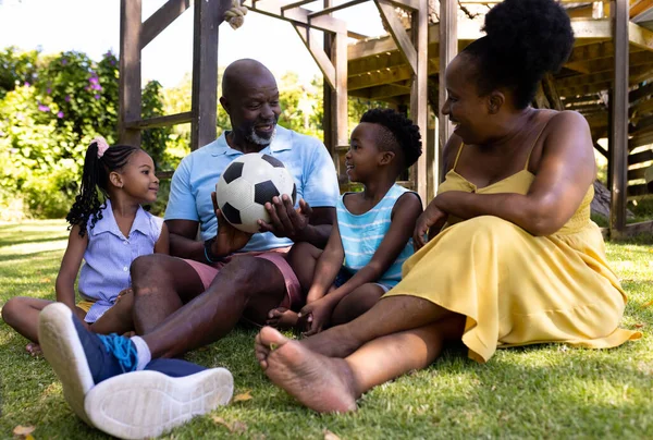 拥有足球的非裔美国祖父母和孙子孙女们坐在公园的草地上 不变的家庭 娱乐和周末观念 — 图库照片