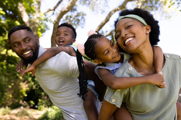 非裔美国人的父母在操场上骑着快乐的女儿和儿子 不变的家庭 享受和周末的概念 — 图库照片