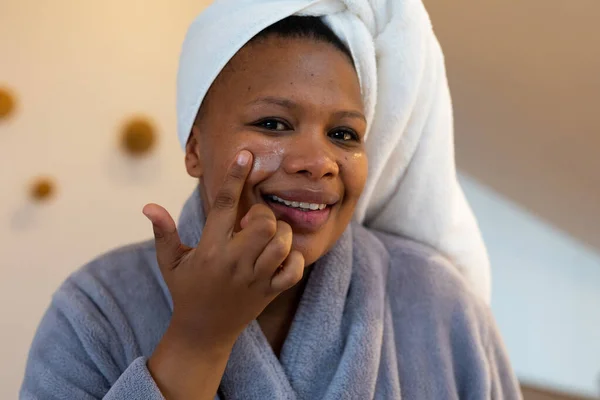 快乐加尺寸的非洲女人 身穿长袍 在浴室涂面霜 自我照顾 健康和美 身体包容和生活方式 — 图库照片
