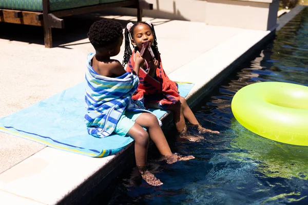 Africký Americký Chlapec Sdílet Svou Zmrzlinu Sestrou Zatímco Sedí Bazénu — Stock fotografie