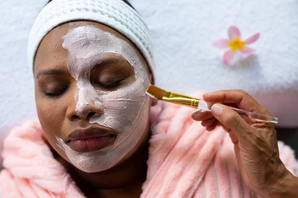 リラクゼーションプラスサイズスパで顔に適用される美容フェイスマスクを持つアフリカ系アメリカ人女性 セルフケア 健康と美しさ 身体の包容力とライフスタイル 変わらない — ストック写真